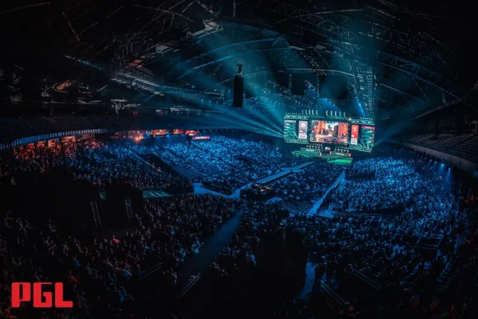 Atmospheric view of a packed esports arena during a major CS2 tournament, featuring vibrant blue lighting and a large crowd watching a central stage with multiple gaming screens displaying live action, highlighting the expansion to 32 teams in the competition