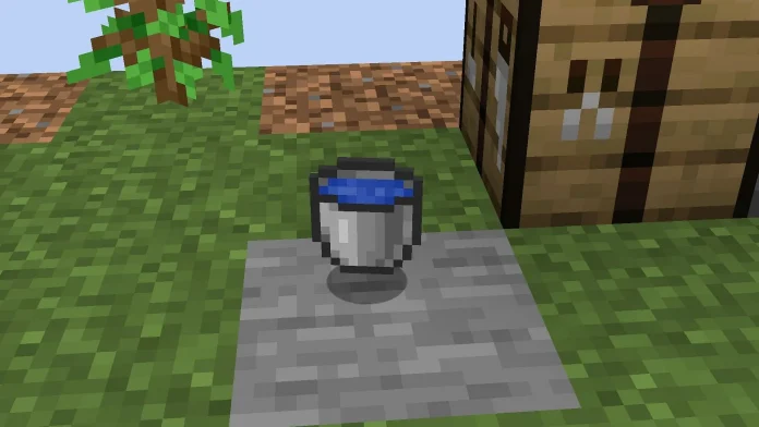 Screenshot from Minecraft showing a bucket filled with water placed on a cobblestone tile in a grassy environment, illustrating how players can obtain water in Minecraft's OneBlock mode.